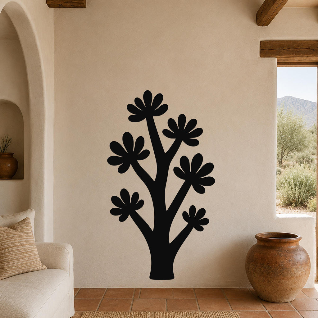 Black metal wall art in a stylized tree shape with flower-like cutouts, mounted on a beige wall above a sofa in a living room.