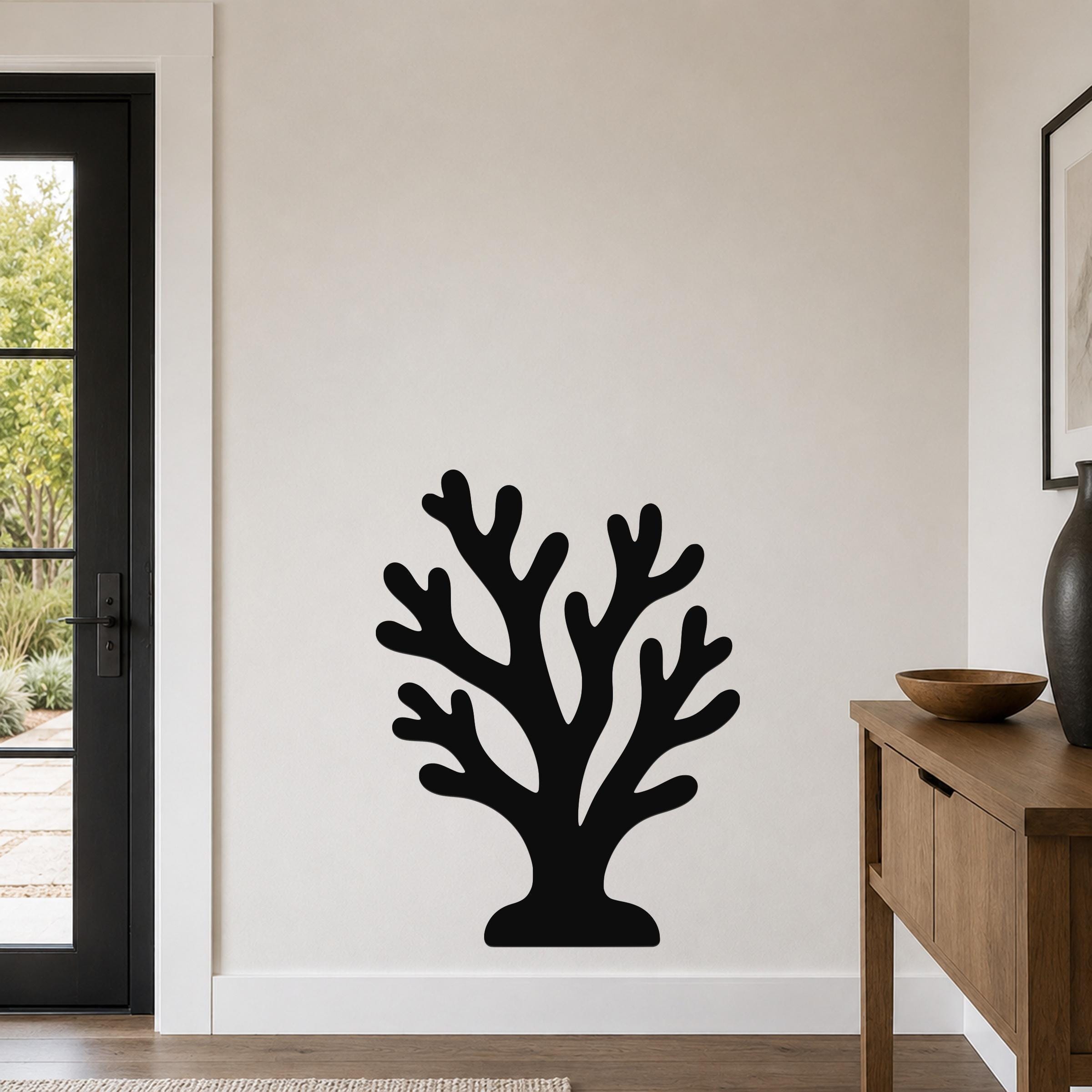 Black metal coral wall art with branching cutouts, mounted on a living room wall above a wooden console table.