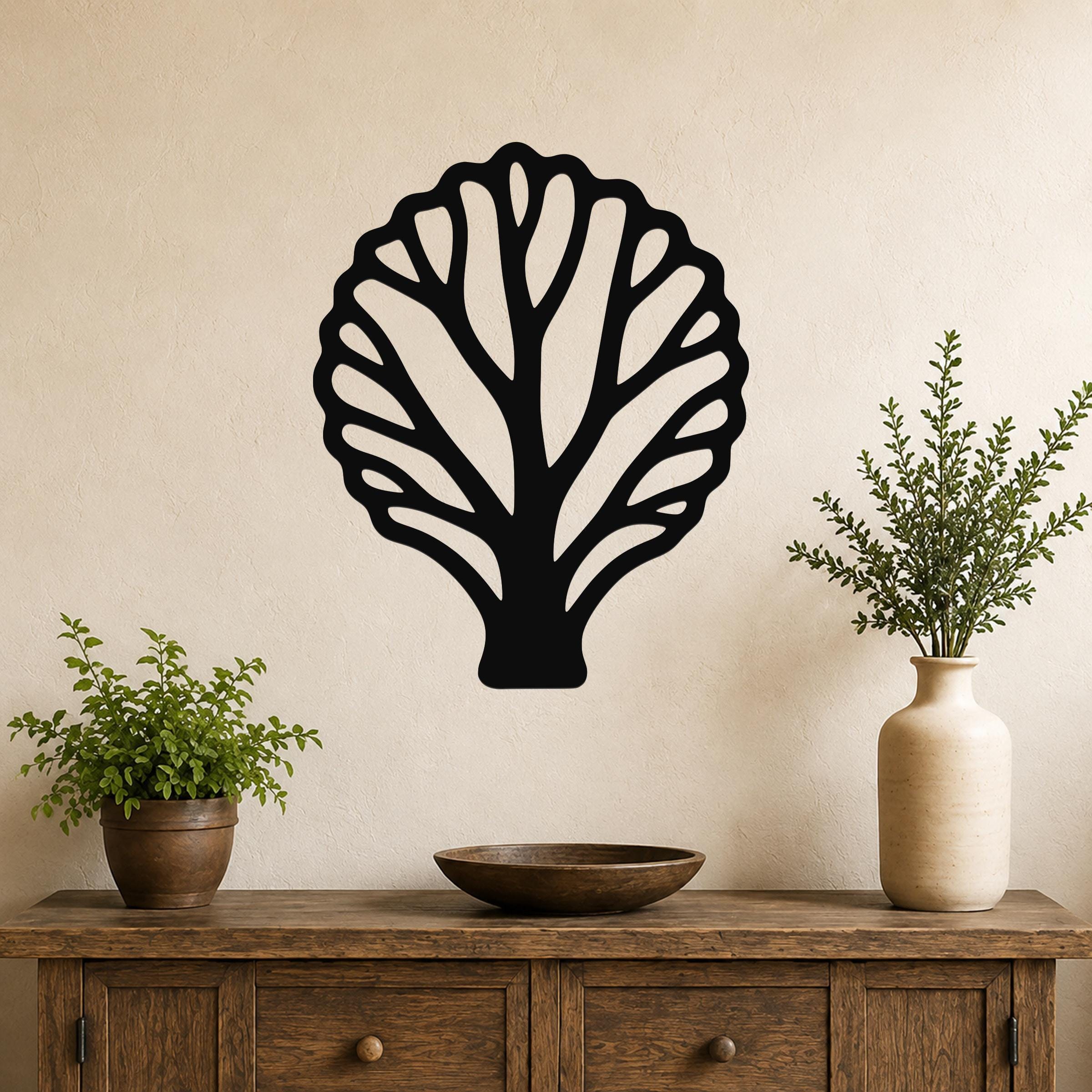 Black metal fan coral wall art with intricate cutout branches, mounted on a beige wall above a wooden console table with potted plants.