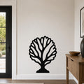 Black metal fan coral wall art with intricate cutout branches, mounted on a white wall in a modern entryway.