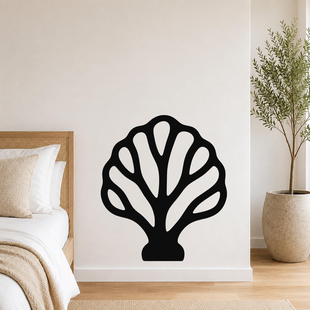 Black metal wall art in a fan coral silhouette with internal cutouts, mounted on a white bedroom wall above a bed.