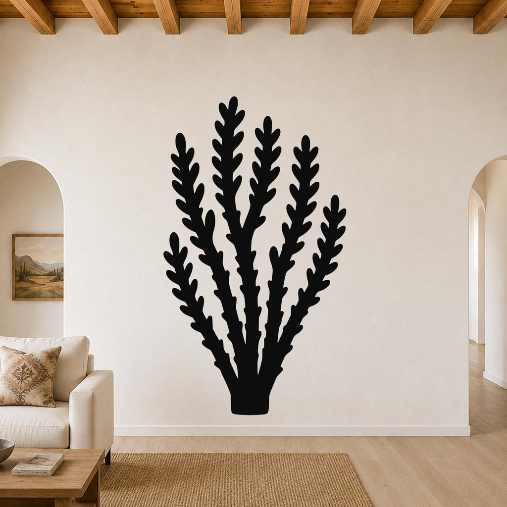 Black metal wall art in a desert branch silhouette, mounted on a living room wall above a sofa.
