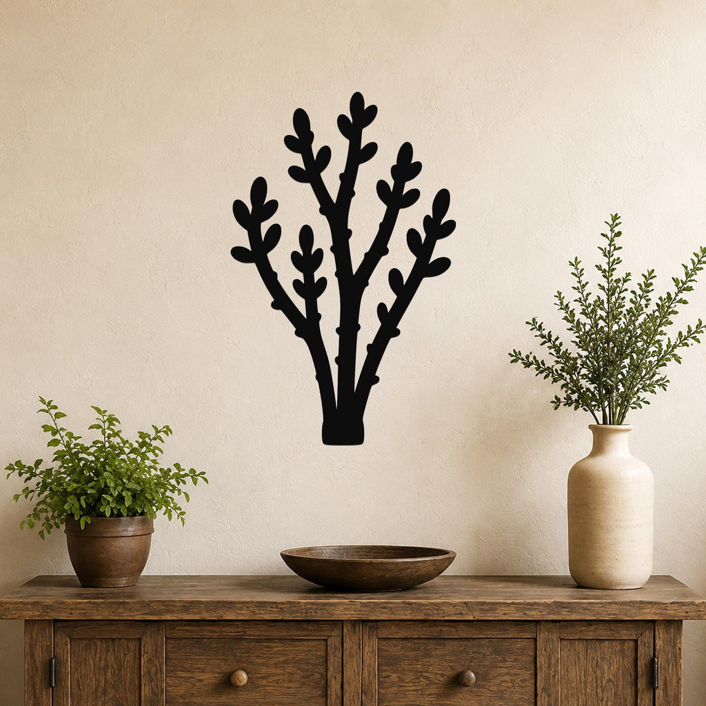 Black metal wall art in a desert branch silhouette design, mounted on a beige wall above a wooden console table with potted plants.