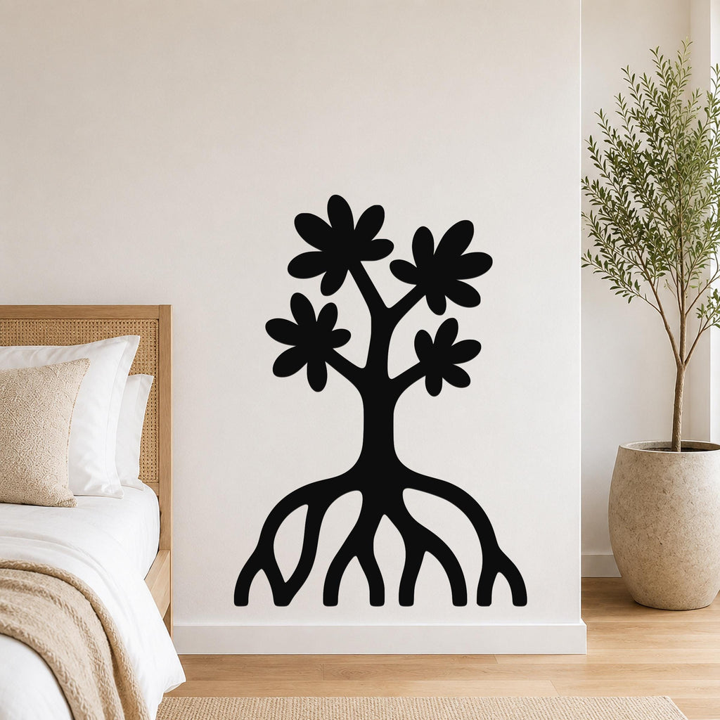 Black metal wall art in a tree silhouette with flower cutouts and exposed roots, mounted on a bedroom wall above a bed.