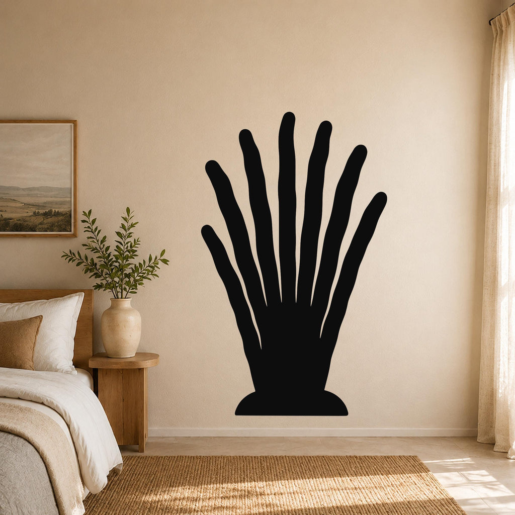 Black metal wall art in a silhouette of a hand with elongated fingers, mounted on a beige bedroom wall above a woven rug.