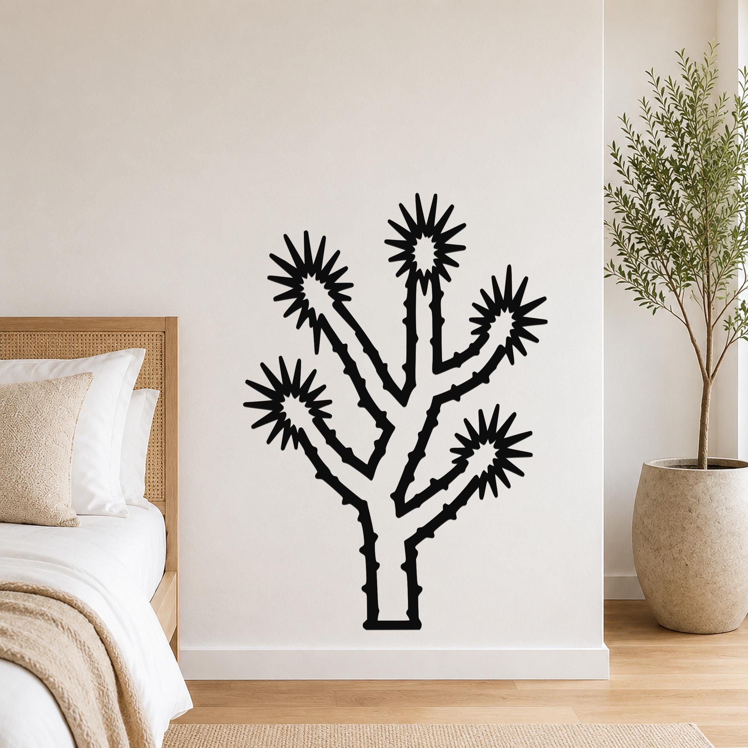 Black metal Joshua tree wall art with starburst cutouts, mounted on a white bedroom wall above a bed.