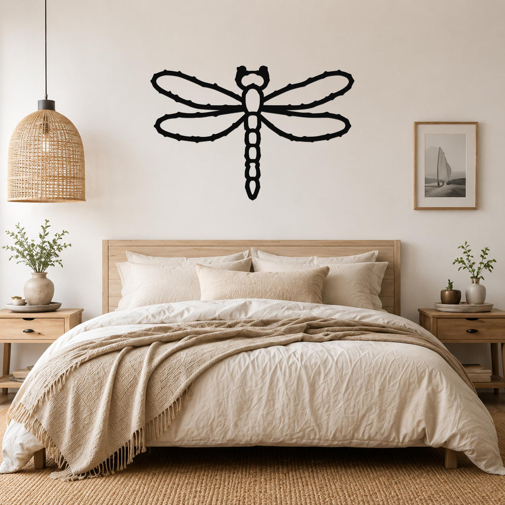 Black metal dragonfly wall art with detailed wing and body cutouts, mounted above a wooden bed in a neutral bedroom.