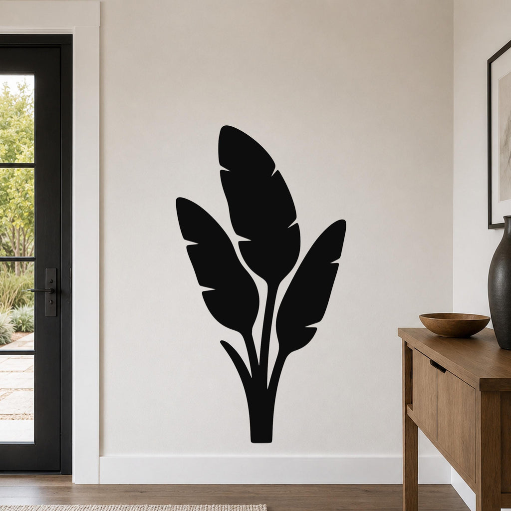 Black metal wall art featuring a tropical leaf silhouette, mounted on a living room wall above a wooden console table.
