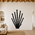 Black metal ocotillo wall art with spiky branch cutouts, mounted on a living room wall above a sofa.