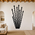 Black metal ocotillo wall art with spiky branch cutouts, mounted on a living room wall above a sofa.