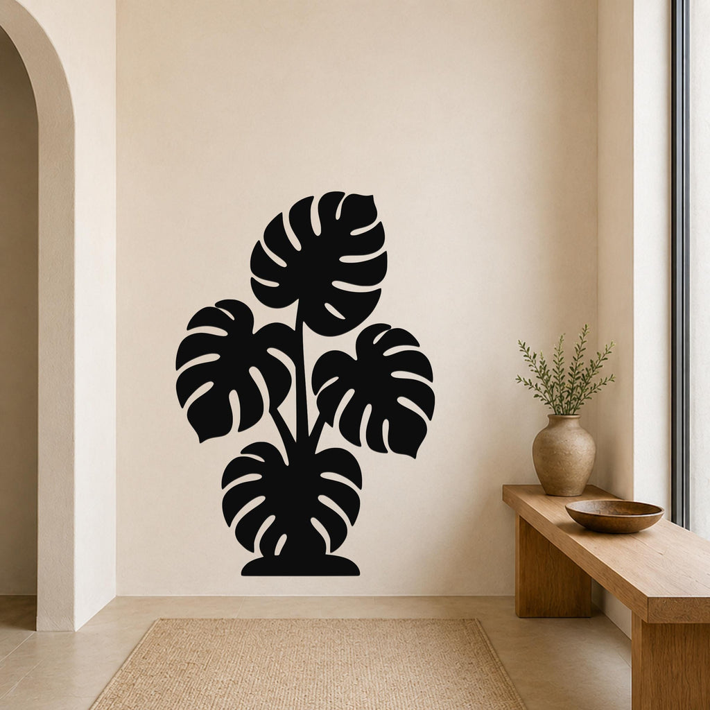 Black metal wall art silhouette of a monstera plant with large leaf cutouts, mounted on a beige wall above a wooden bench in a living room.