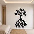 Black metal wall art of a tree with flower-shaped leaves and exposed roots, mounted on a bedroom wall above a bed.