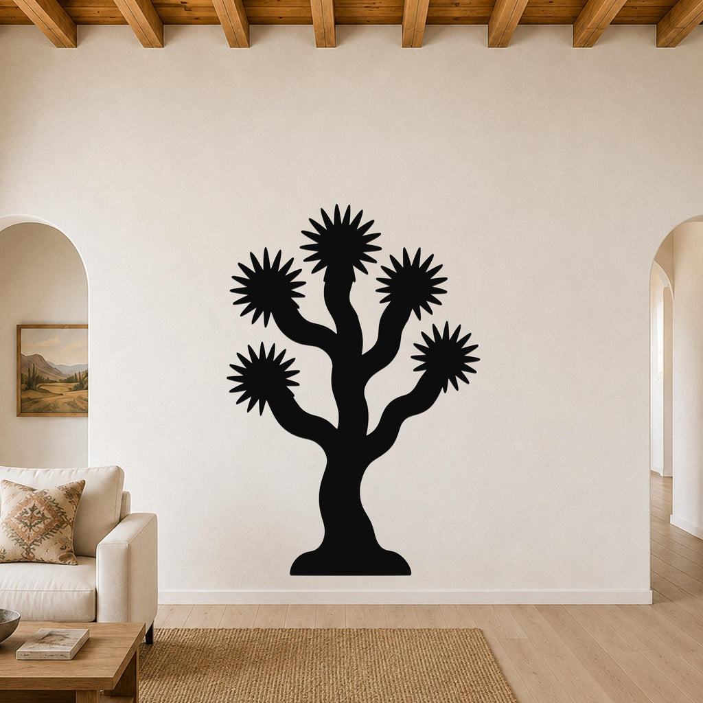 Black metal Joshua tree wall art with starburst-shaped branches, mounted on a living room wall above a sofa.
