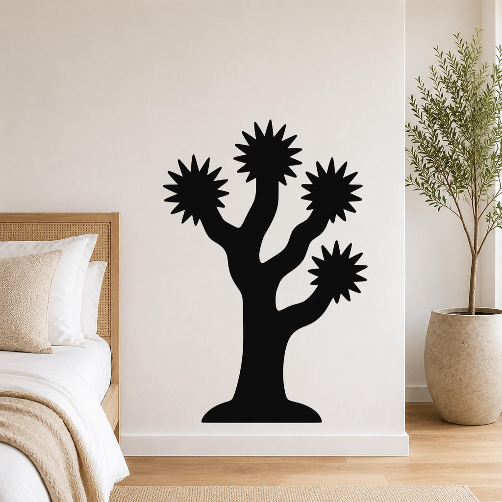 Black metal Joshua tree wall art with starburst-shaped branches, mounted on a white bedroom wall above a bed.