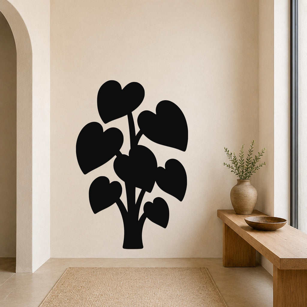 Black metal wall art in the silhouette of a plant with heart-shaped leaves, mounted on a beige wall above a wooden bench in a minimalist entryway.