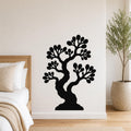 Black metal wall art silhouette of a bonsai tree with layered branches and leaf clusters, mounted on a white bedroom wall above a bed.