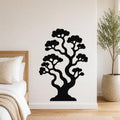 Black metal wall art in the silhouette of a bonsai tree with curved branches and cloud-like foliage, mounted on a white wall above a bed in a bedroom.