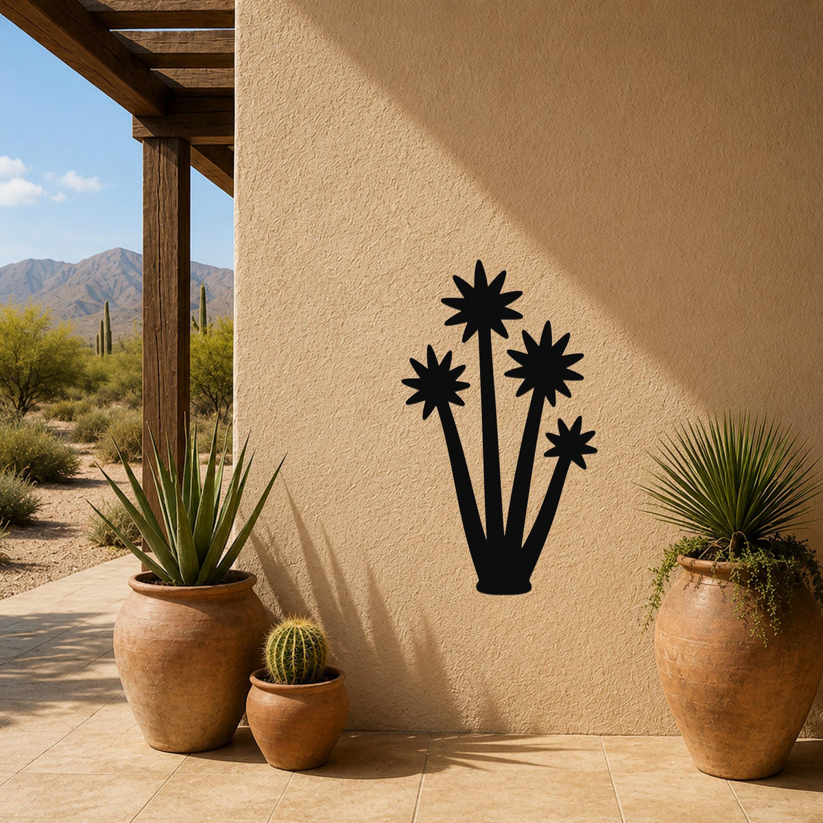 Black metal yucca wall art with star-shaped bloom cutouts, mounted on a stucco outdoor wall above potted plants on a patio.
