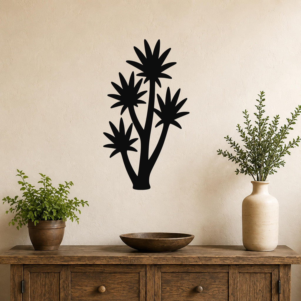 Black metal yucca wall art with four star-shaped leaf cutouts, mounted on a beige wall above a wooden console table with potted plants.