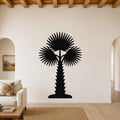 Black metal palm tree wall art with fan-shaped fronds and a textured trunk, mounted on a living room wall above a sofa.