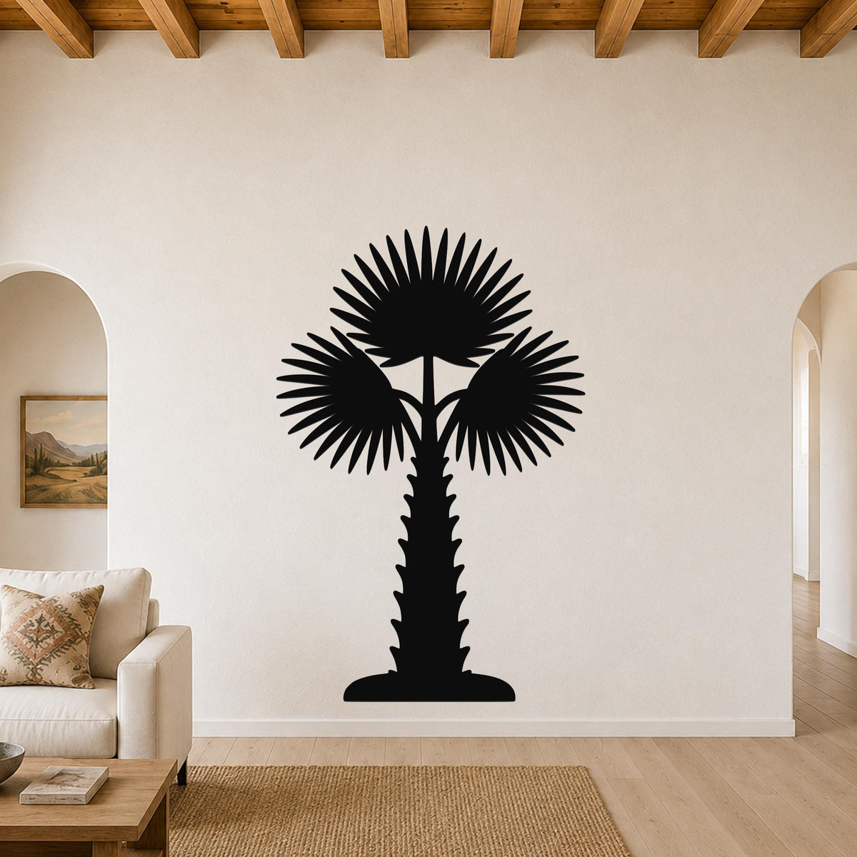 Black metal palm tree wall art with fan-shaped fronds and a textured trunk, mounted on a living room wall above a sofa.