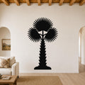 Black metal palm tree wall art with fan-shaped fronds and a textured trunk, mounted on a living room wall above a sofa.