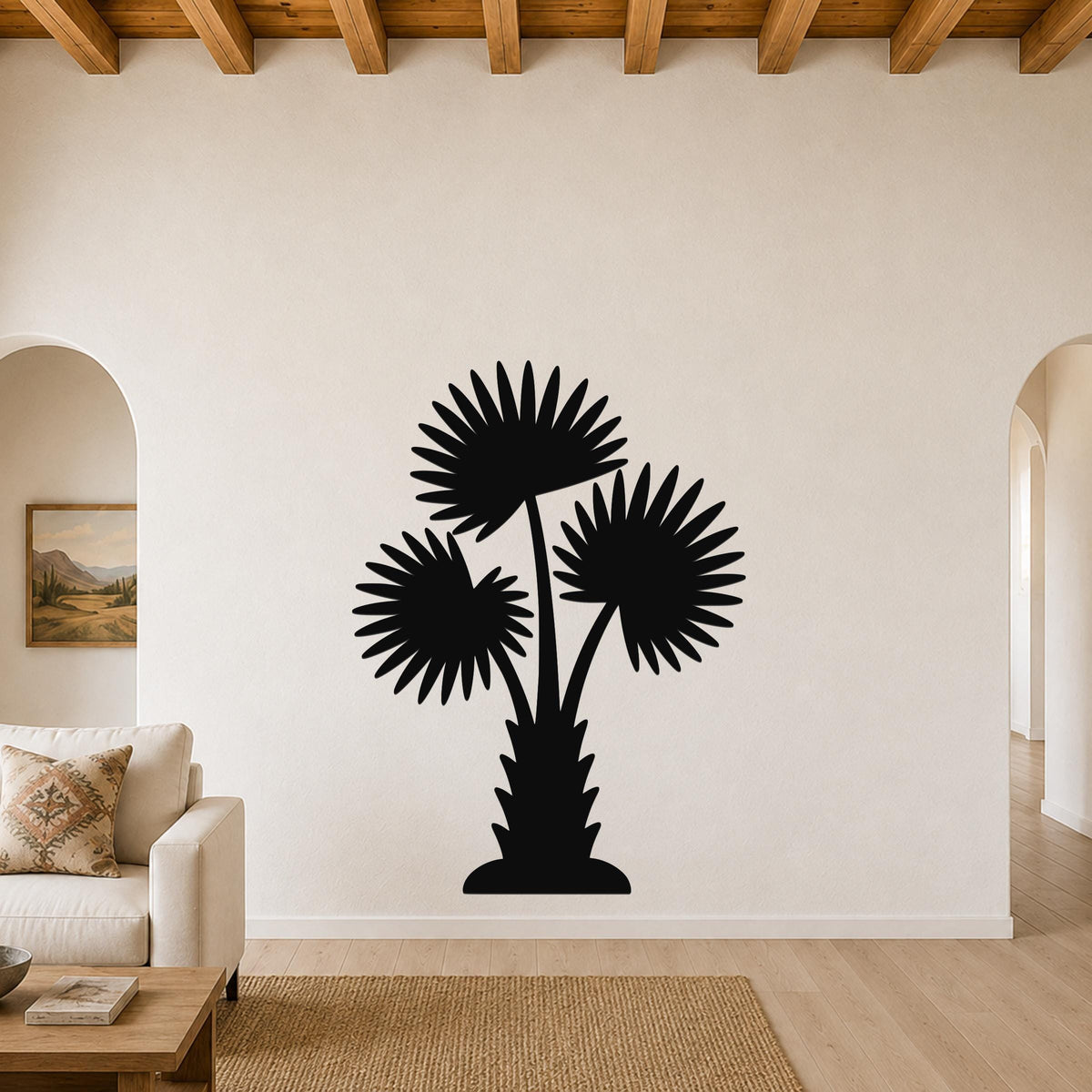 Black metal wall art silhouette of a California fan palm tree with three fronds, mounted on a living room wall above a sofa.