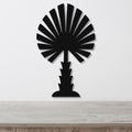 Black metal palm tree wall art with fan-shaped fronds and a textured trunk, mounted on a white wall above a light wood countertop.