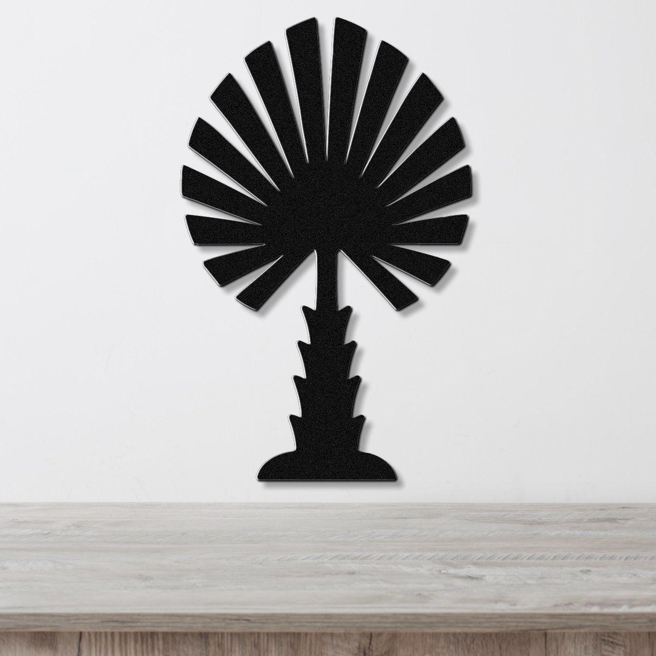 Black metal palm tree wall art with fan-shaped fronds and a textured trunk, mounted on a white wall above a light wood countertop.