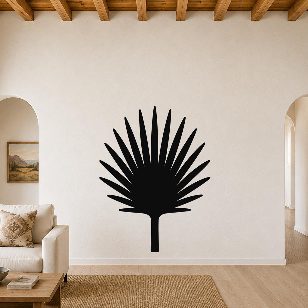 Black metal fan palm tree wall art with radiating leaf cutouts, mounted on a living room wall above a sofa.