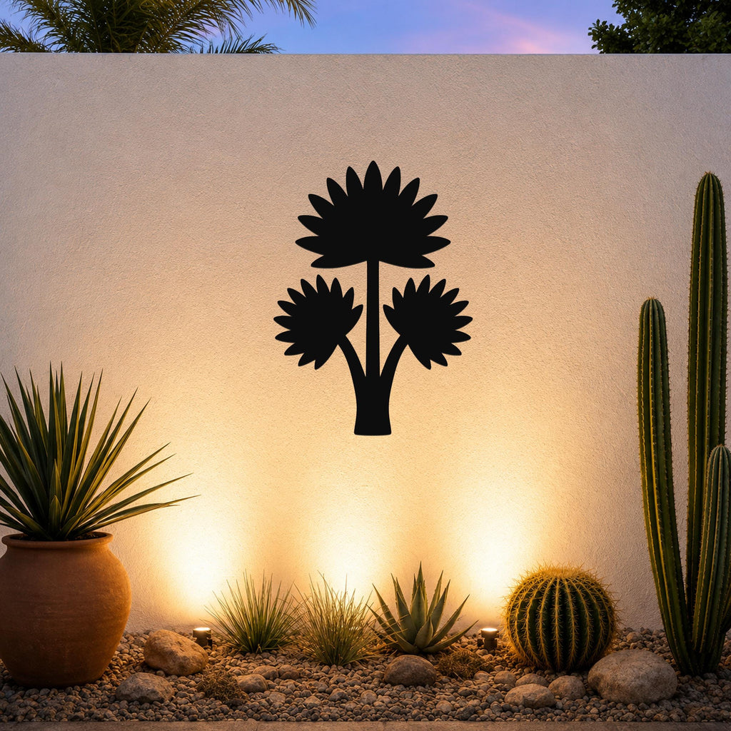 Black metal wall art featuring a fan palm tree silhouette with three leaf clusters, mounted on an outdoor wall above a desert garden with cacti and warm uplighting.
