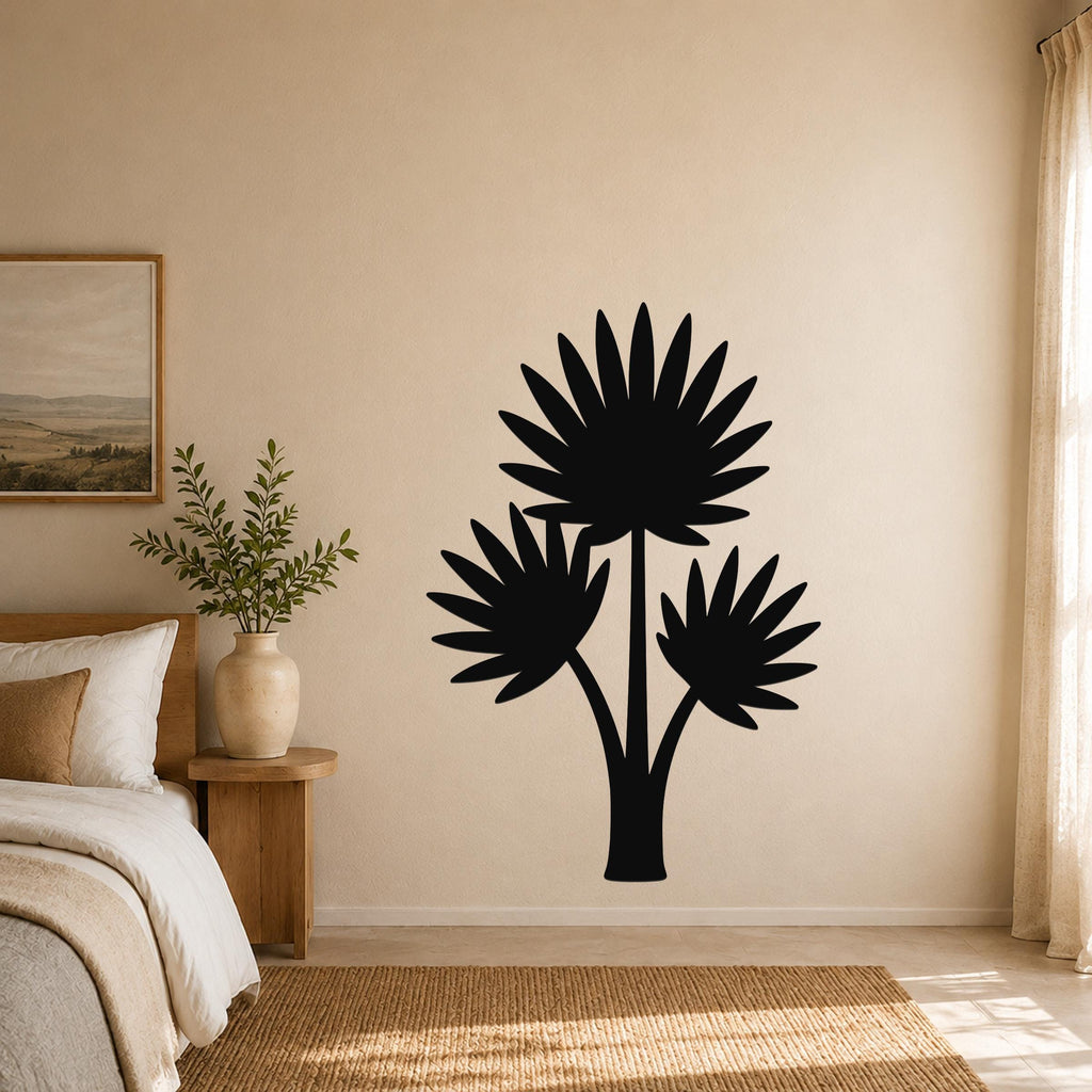Black metal wall art silhouette of a fan palm tree with three fronds, mounted on a beige bedroom wall above a bed.