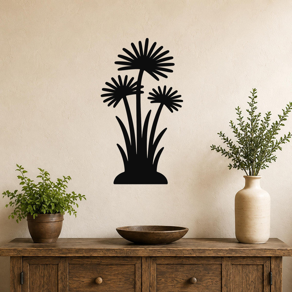 Black metal wall art featuring a silhouette of three daisy-like flowers with long stems and grassy base, mounted on a beige wall above a wooden console table in a living room.