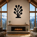 Black metal coral wall art with organic branch cutouts, mounted above a fireplace in a living room with large windows and mountain views.