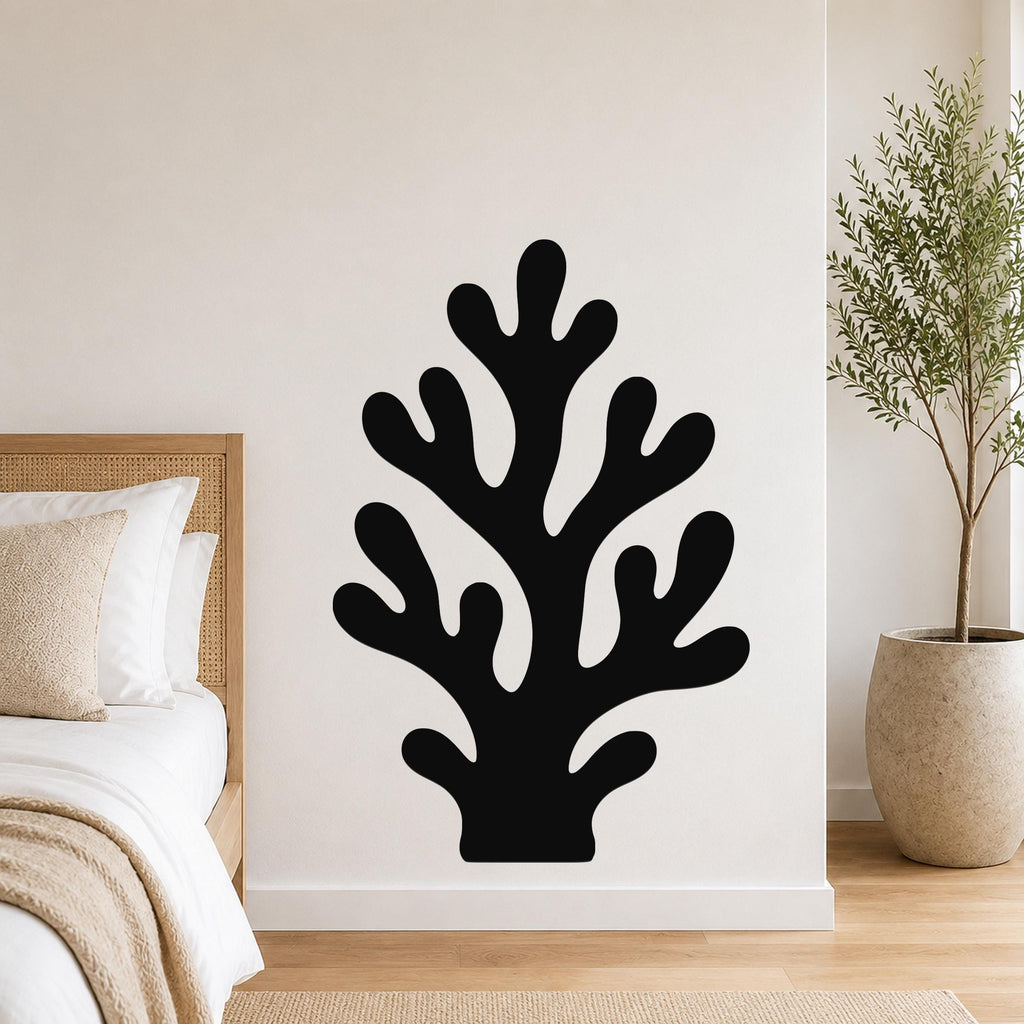 Black metal coral wall art with branching cutouts, mounted on a white bedroom wall above a bed.