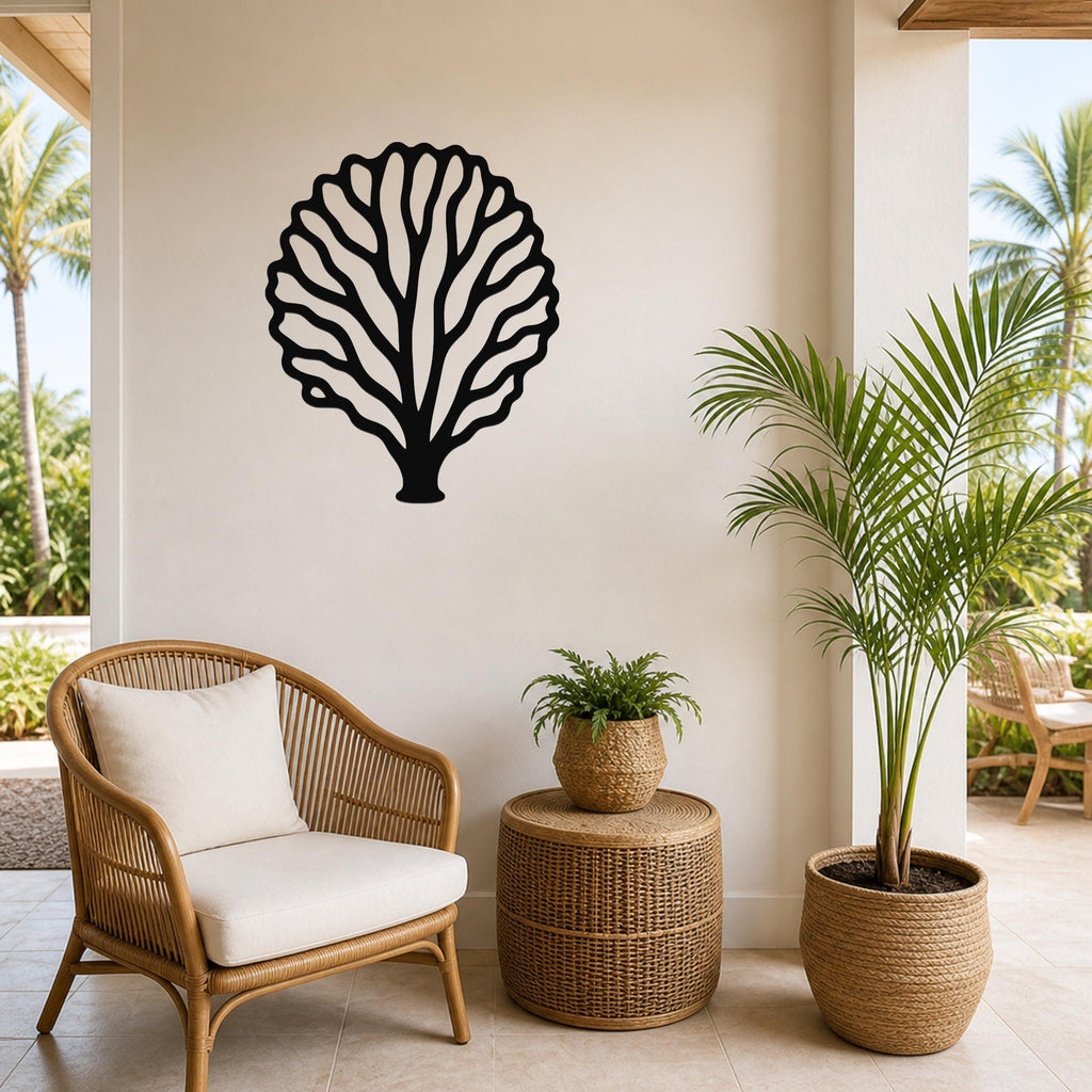 Black metal fan coral wall art with intricate branch cutouts, mounted on a light-colored wall above a wicker chair in a bright patio setting.