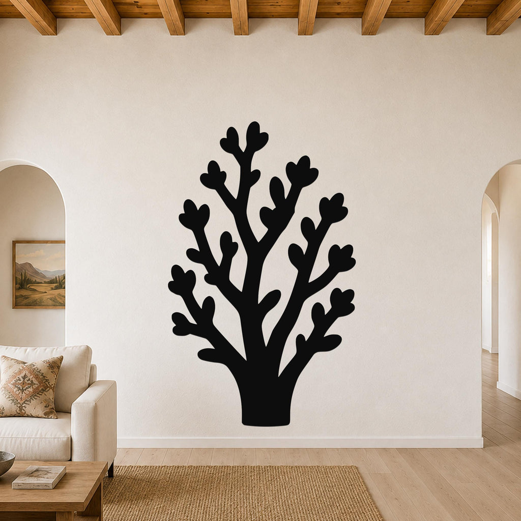 Black metal wall art in a tree silhouette with heart-shaped leaf cutouts, mounted on a living room wall above a sofa.