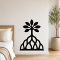 Black metal wall art in a tree silhouette with leafy canopy and exposed root cutouts, mounted on a bedroom wall above a bed.