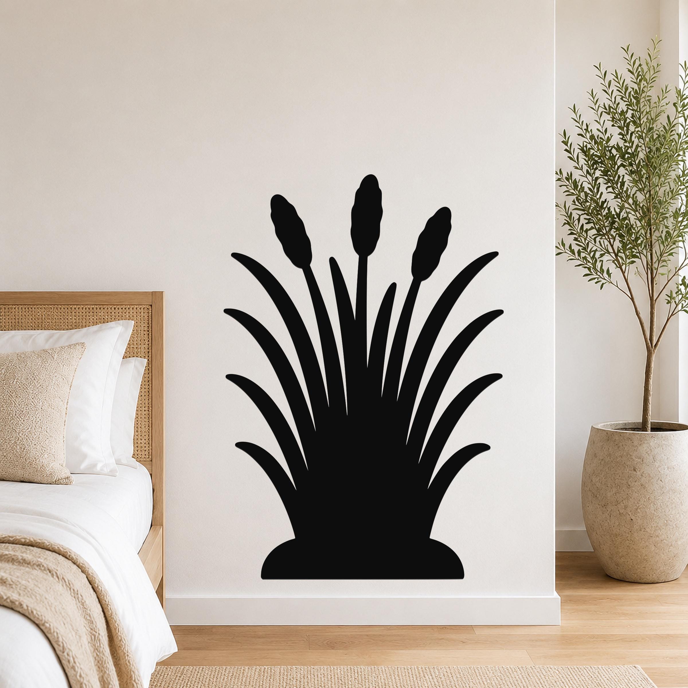 Black metal wall art in a cattail silhouette design, mounted on a bedroom wall above a bed with a woven headboard.