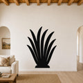 Black metal agave plant wall art with leaf cutouts, mounted on a living room wall above a sofa.