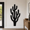 Black metal wall art in the silhouette of a saguaro cactus with branching arms, mounted on a light-colored wall in a modern entryway.
