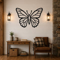 Black metal butterfly wall art with detailed wing cutouts, mounted on a shiplap wall above a wooden console table in a living room.