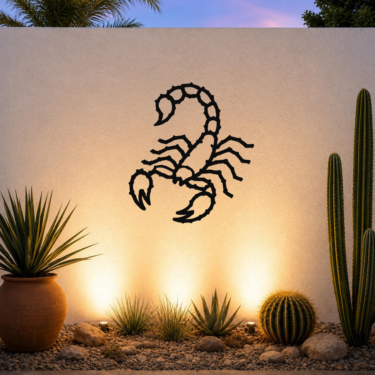 Black metal scorpion wall art with detailed cutout design, mounted on a textured outdoor wall above a desert garden with cacti and warm uplighting.