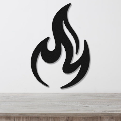 Black metal flame wall art with bold silhouette and internal cutout details, mounted on a white wall above a light wood surface.