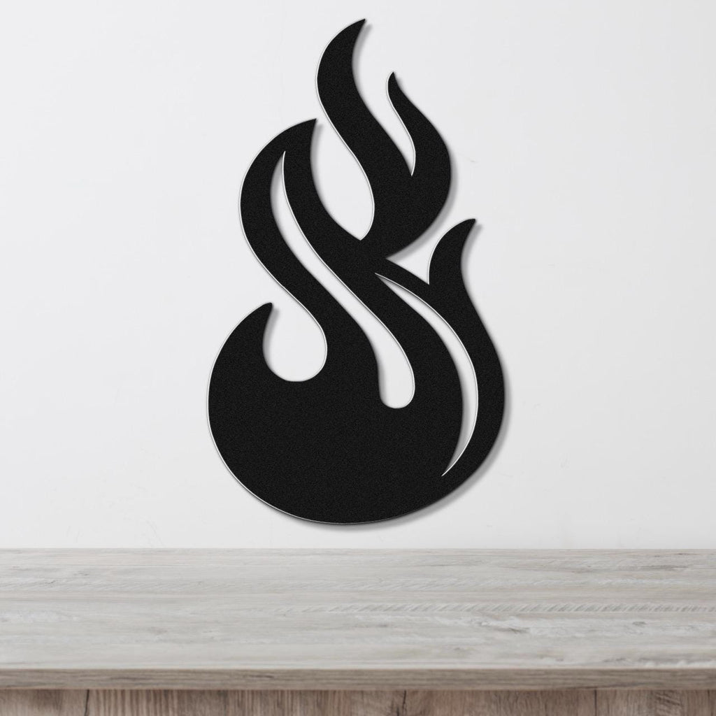 Black metal flame wall art with flowing cutout design, mounted on a white wall above a light wood surface.