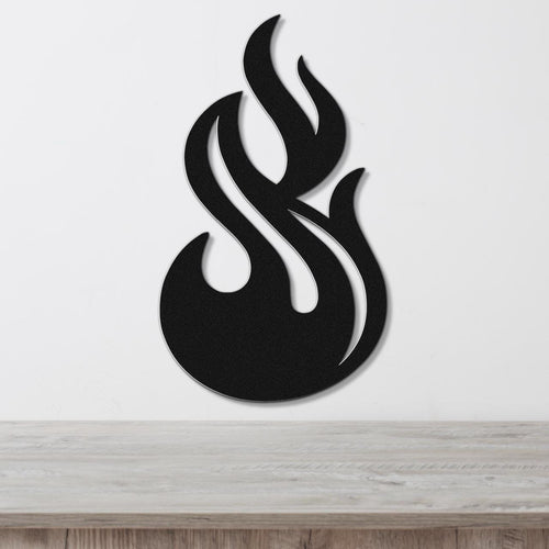 Black metal flame wall art with flowing cutout design, mounted on a white wall above a light wood surface.