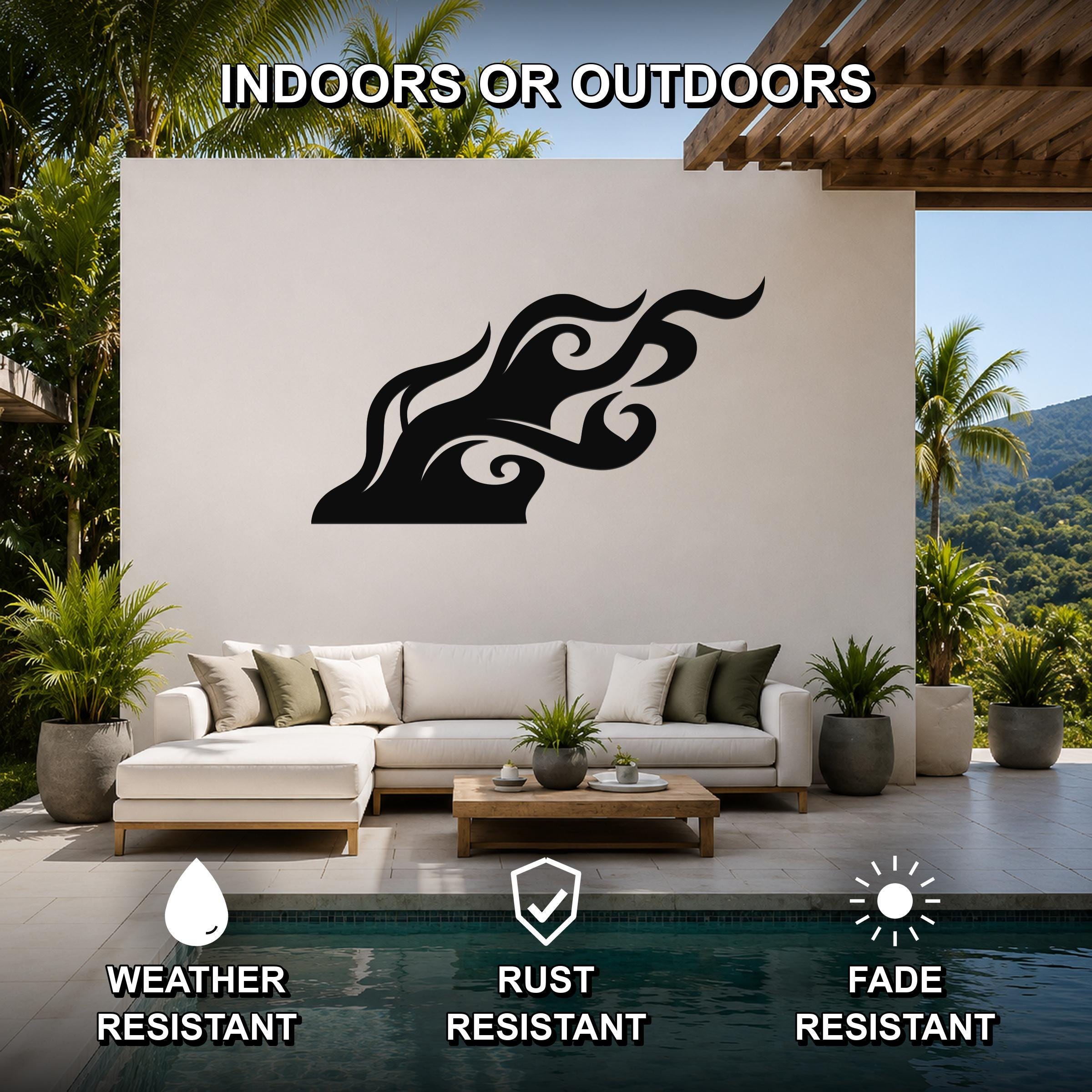 Black metal flame wall art with fluid motion cutouts, mounted on a white outdoor wall above a sofa in a patio living area.
