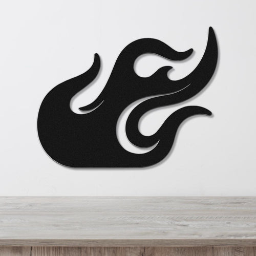 Black metal flame wall art with flowing cutout design, mounted on a white wall above a wooden surface.