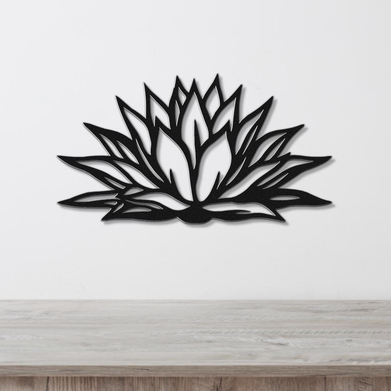 Black metal agave wall art with bold geometric cutouts, mounted on a white wall above a light wood counter.