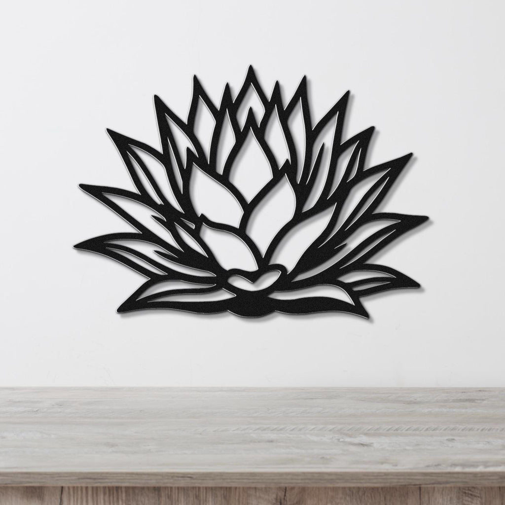 Black metal agave wall sculpture with layered leaf cutouts, mounted on a white wall above a light wood counter.